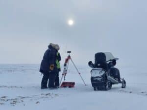 Cambridge Bay land survey, legal land survey Nunavut, Arctic tundra in winter, land surveyor on the arctic tundra with a snowmobile doing a legal survey in Cambridge Bay, Nunavut.